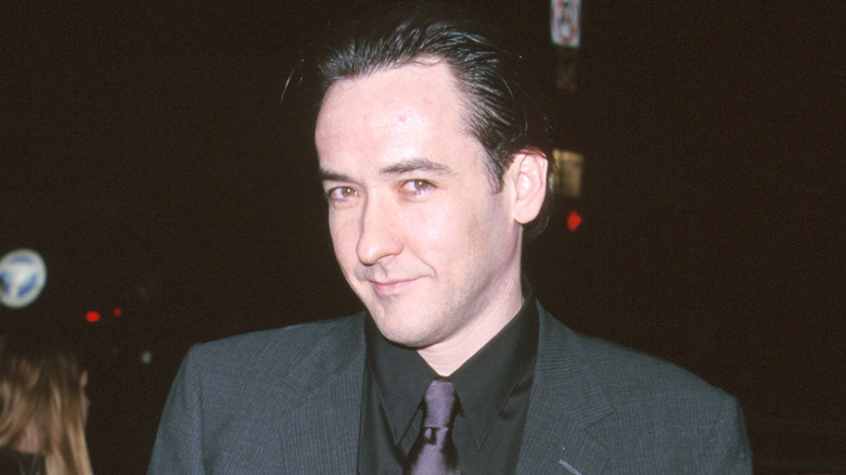 John Cusack smirking while taking a photo