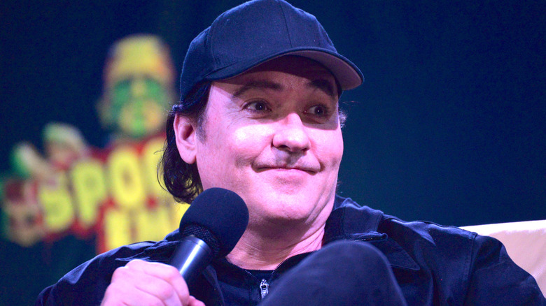 John Cusack holding a microphone during press