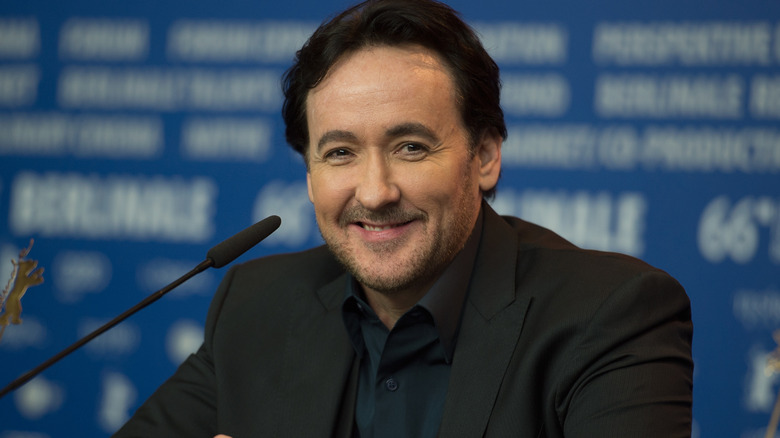 John Cusack sitting down during press
