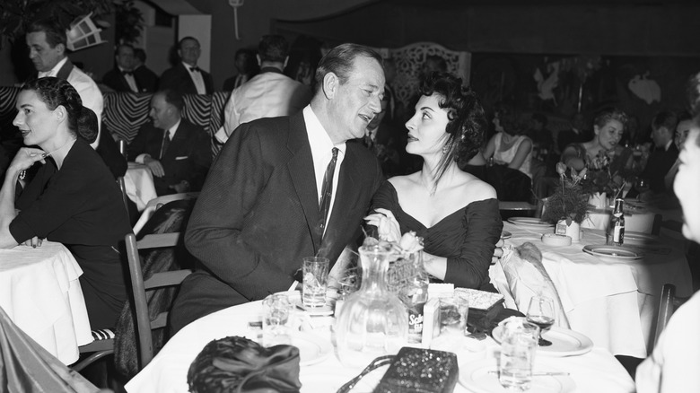 John Wayne and Pilar Pallete Wayne at a dining table looking at each other