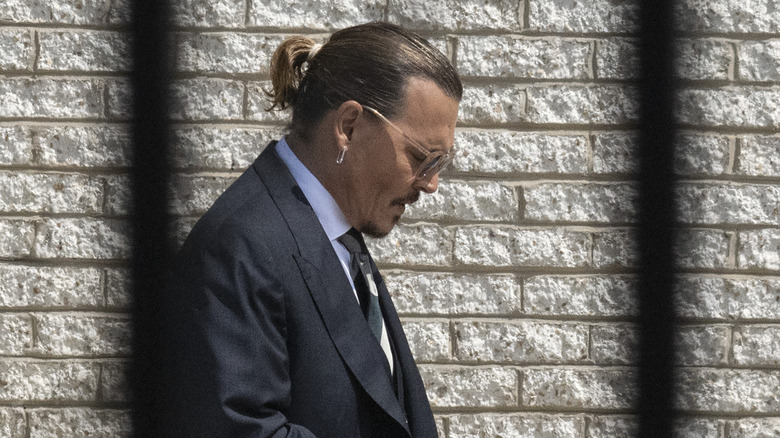 Johnny Depp looking down at the ground behind bars