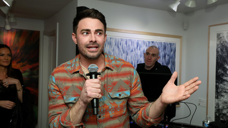Jonathan Bennett talking with microphone and looking to the left.