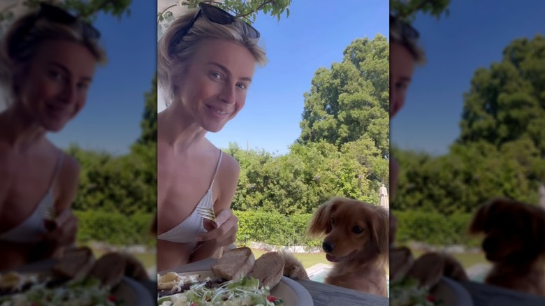 Julianne Hough smiling outdoors while her dog looks at the salad she's eating