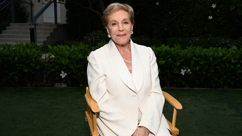 Julie Andrews sitting in a chair outside in an all-white outfit.