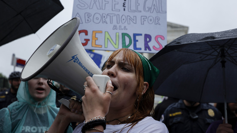 woman speaks into bullhorn, rally for woman's reproductive rights
