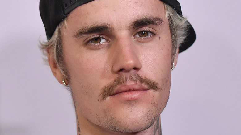 Justin Bieber wears and hat and earrings