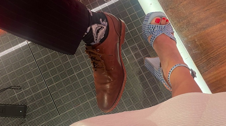 close-up of John Berman's brown dress shoe and Kaitlan Collins' crystal-embellished blue sandal with a chunky heel.