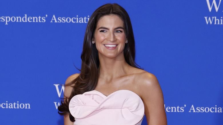 Kaitlan Collins smiling in a strapless blush gown with folded detailing.