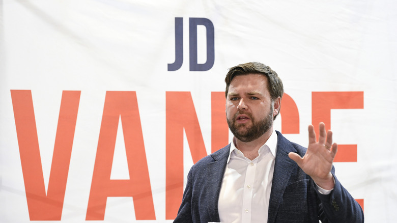 JD Vance speaking while holding a hand up
