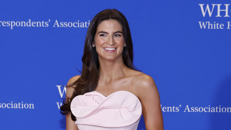 Kaitlan Collins looking to the side and smiling in a light pink dress