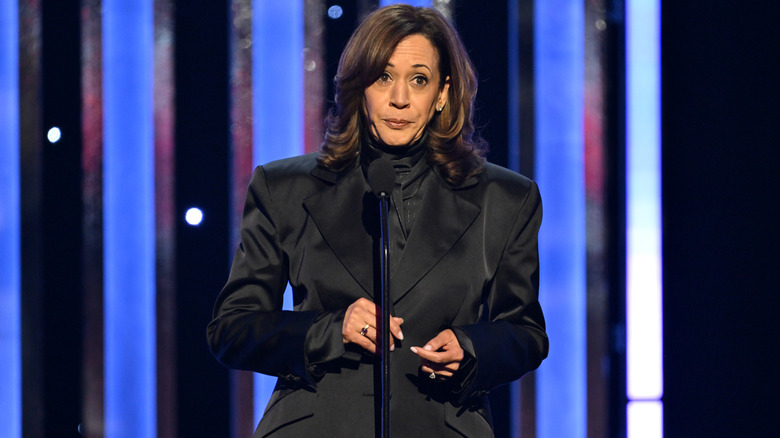 Kamala Harris giving a speech onstage in an all-black outfit