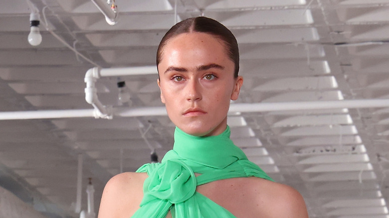 Ella Emhoff walking on the catwalk with a green scarf around her neck