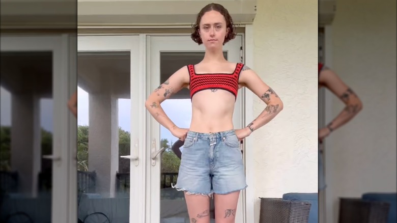 Ella Emhoff posing on some steps in a tiny body baring crochet crop top and denim shorts