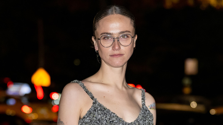 Ella Emhoff standing outside at night in glasses and a strappy grey dress