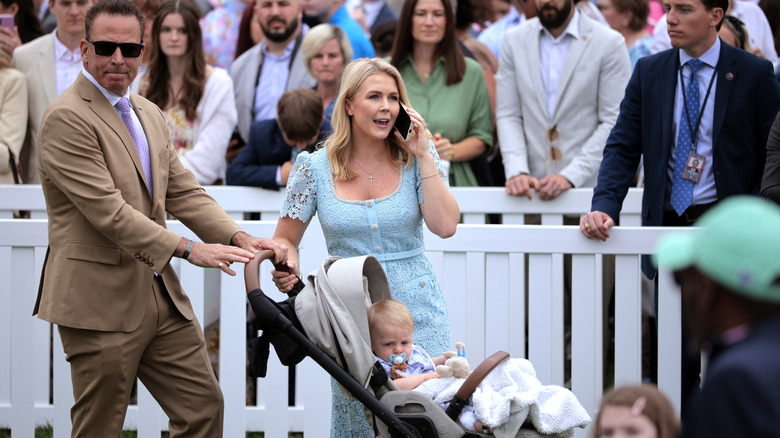 Karoline Leavitt speaking on the phone while her husband pushes their baby's stroller