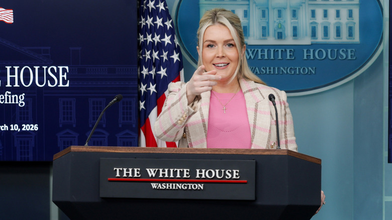 Karoline Leavitt at podium pink plaid jacket pink shirt