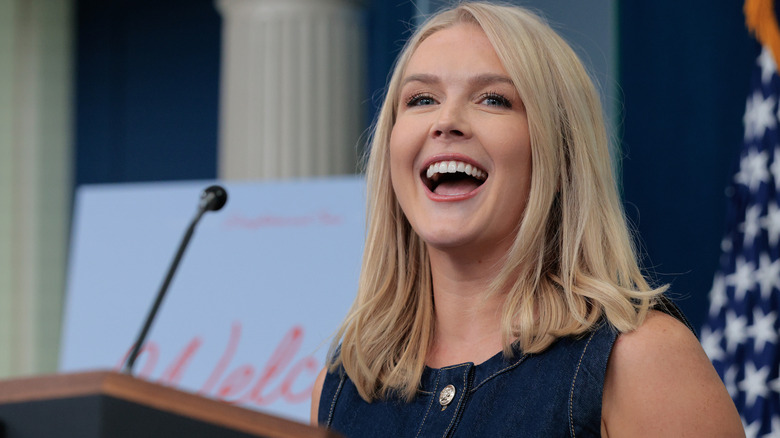 Karoline Leavitt laughing behind podium