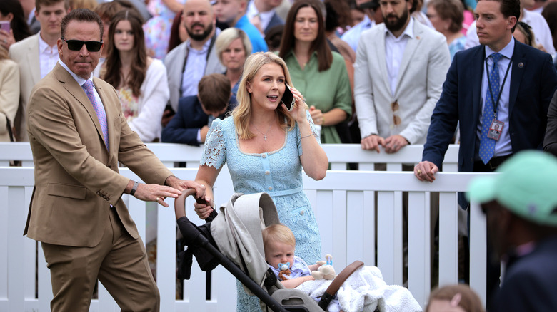 Karoline Leavitt talking on the phone while her husband pushes a stroller