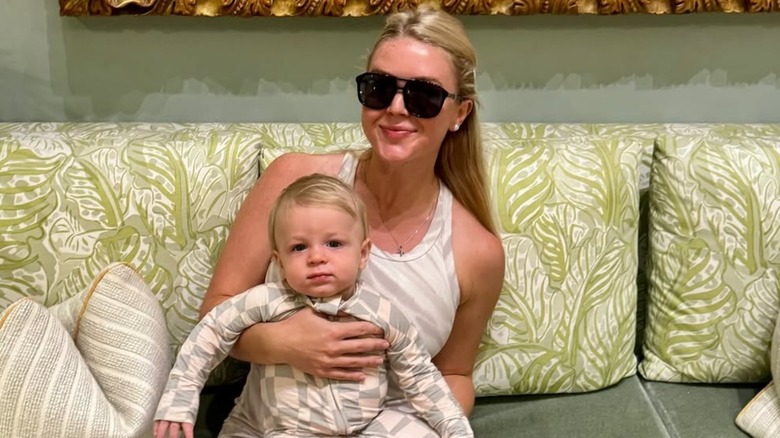 Karoline Leavitt smiling, wearing sunglasses, and holding her son