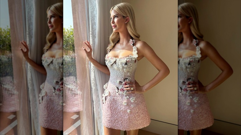 Melania Trump gazes out of a window while wearing a sequined pink dress with floral details