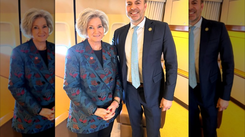 Susie Wiles poses next to a suit-clad man while wearing a colorful, expensive blazer