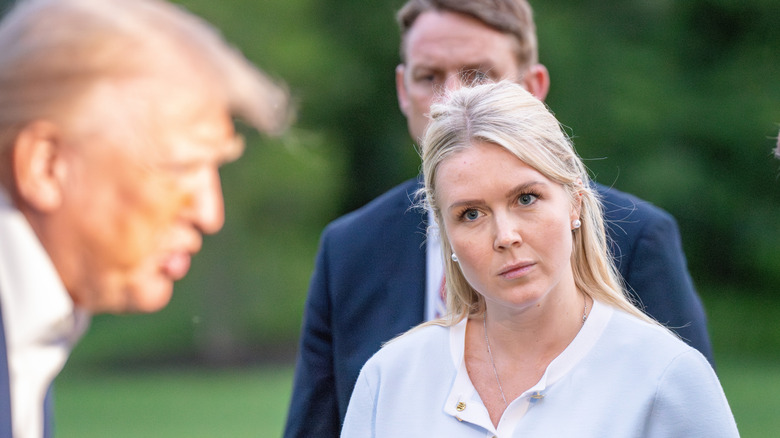 Karoline Leavitt listens as Donald Trump talks to members of the media in Washington, DC (2025)