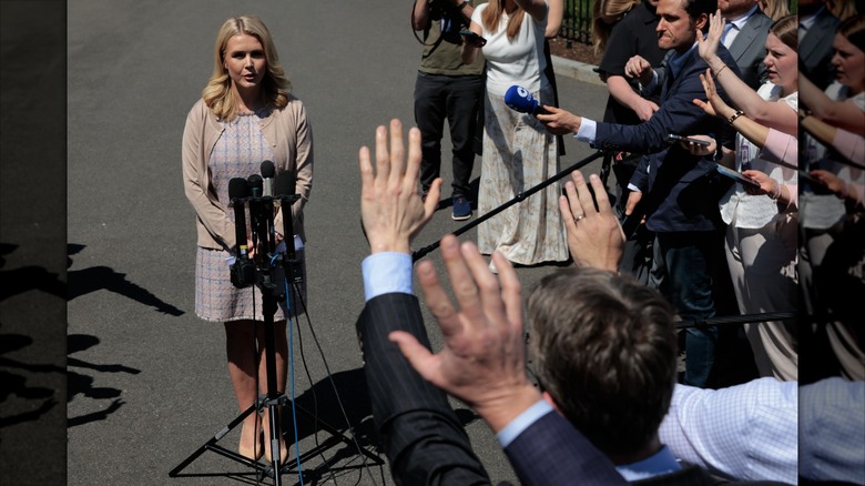 Karoline Leavitt at a microphone outside surrounded by press.