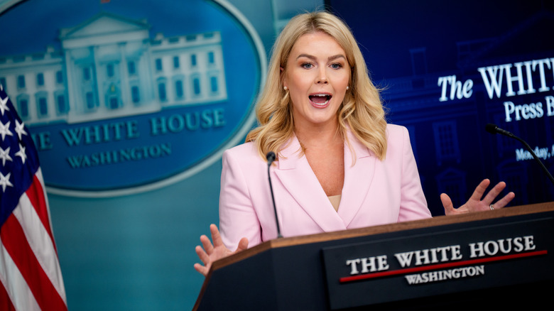 Karoline Leavitt giving a White House press briefing in a pink suit