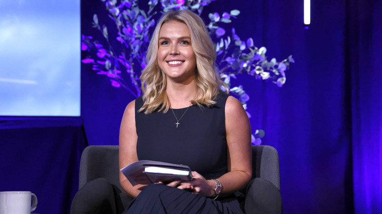 Karoline Leavitt smiles while sitting onstage