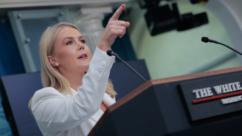 Karoline Leavitt pointing during a press briefing in a white blazer
