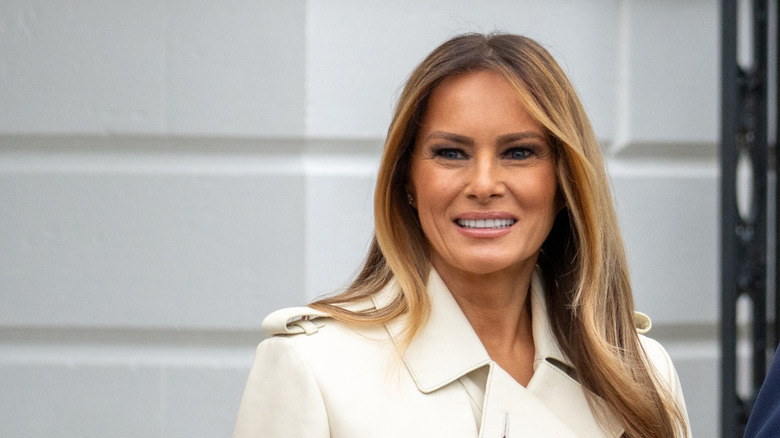 Melania Trump half smile white coat