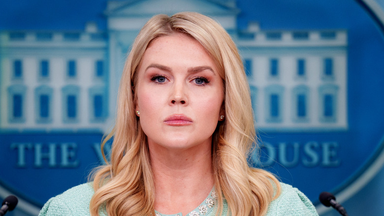 Karoline Leavitt wearing a light blue outfit while hosting a press conference at the White House and taking a question from a reporter.
