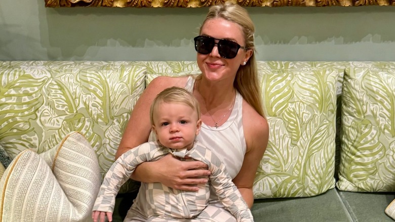 Karoline Leavitt smiling and wearing sunglasses while she holds her son