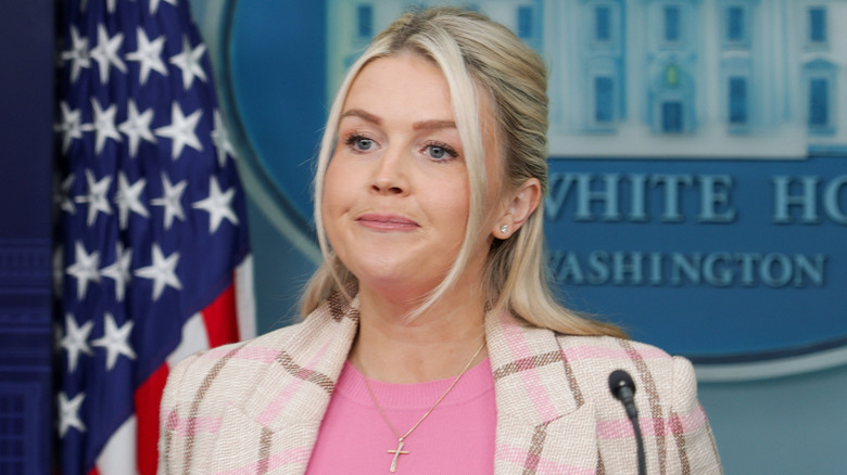 Karoline Leavitt frowning in the White House press briefing room.
