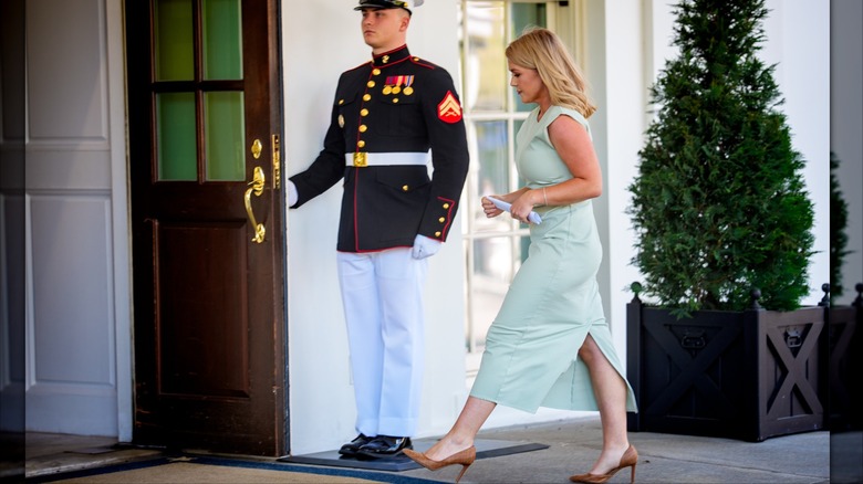 Karoline Leavitt walking into the White House wearing an ankle length mint-green dress with a back slit up above her knee