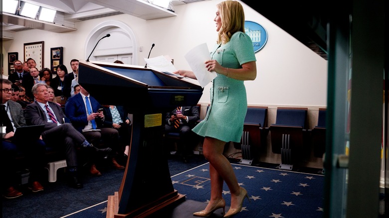 Karoline Leavitt approaching White House podium wearing short green dress