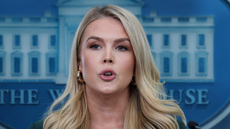 Karoline Leavitt wearing a green blazer while speaking to reporters during a press briefing.