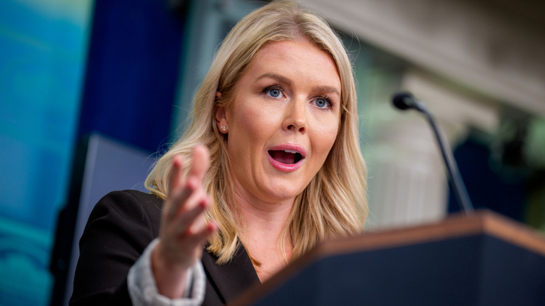 Karoline Leavitt gesturing with her mouth open behind a podium.