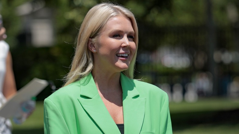 Karoline Leavitt smiling while outside in a green blazer.