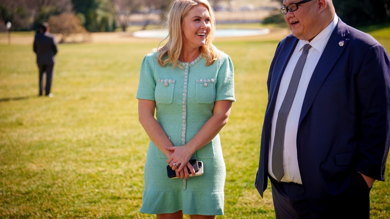 Karoline Leavitt, smiling outside with a mint colored dress.