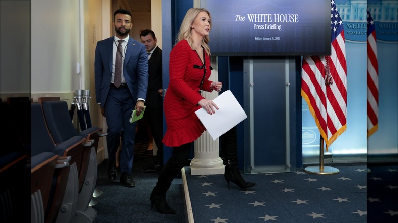 Karoline Leavitt stepping up onto the White House platform with papers.