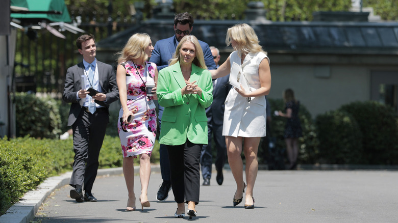 Karoline Leavitt with her hands folded with her team behind her.