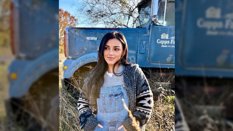 Alexis Wilkins standing in front of a blue truck in a field.