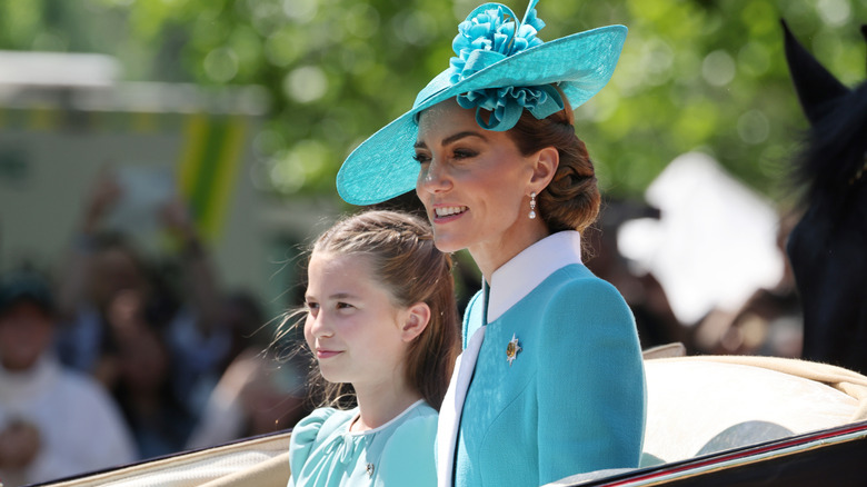Princess Charlotte and Kate Middleton smiling in a carriage