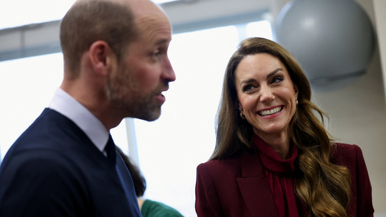 Kate Middleton smiling at a talking Prince William
