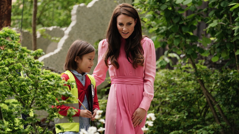 Kate Middleton wearing pink dress walking with young girl 