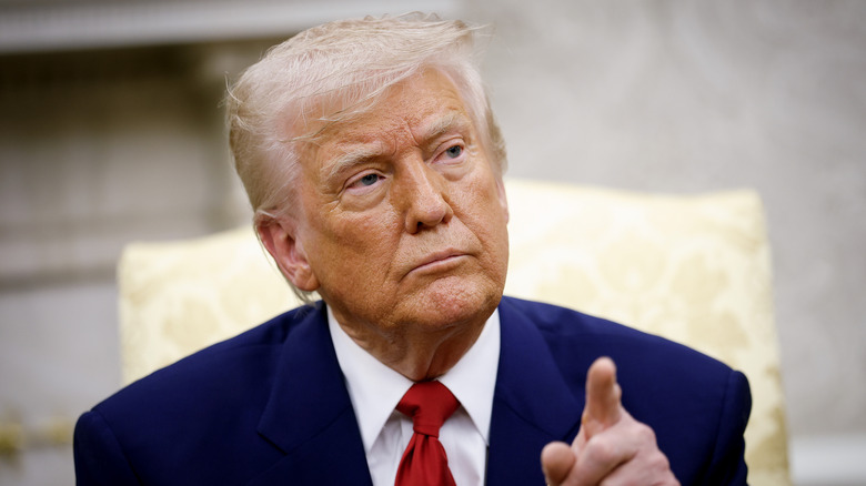 Donald Trump pointing in a navy suit with a red tie