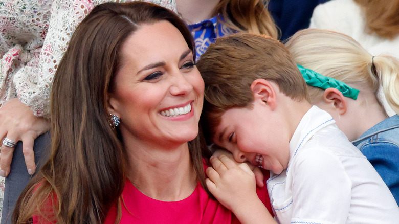 Kate Middleton smiling and holding Prince Louis