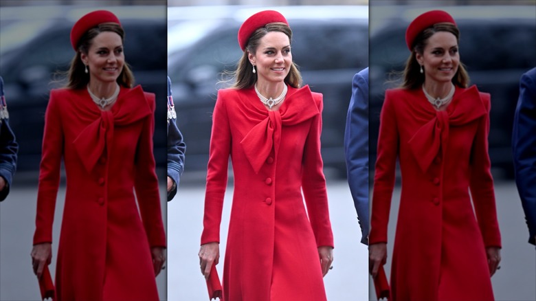 Kate Middleton in a red hat and red dress with a large bow on it.