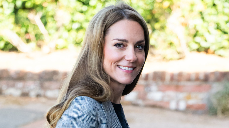 Kate Middleton smiling over her shoulder while outside.